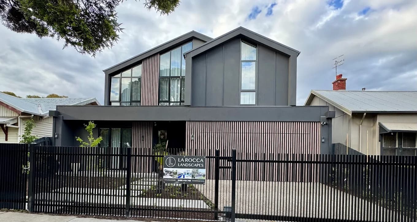 Black vertical slat front fence and sliding driveway gate in front of a new two-storey house